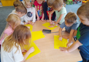 Dzieci kalkują obrazek pocierając kredką karton nałożony na trójwymiarowy kontur.